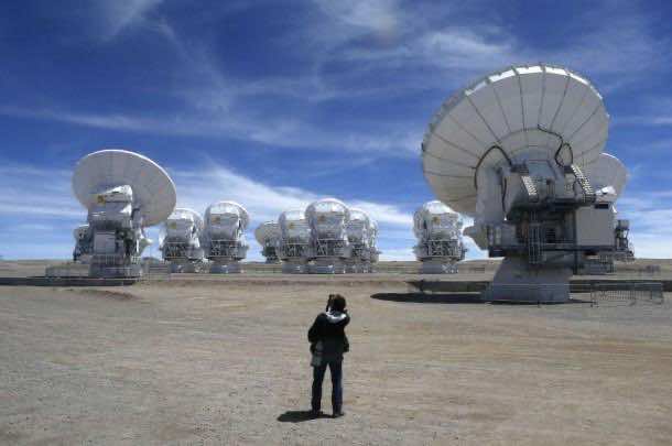 A member of the media takes pictures of the parabolic antennas of the ALMA project at the El Llano de Chajnantor in the Atacama desert