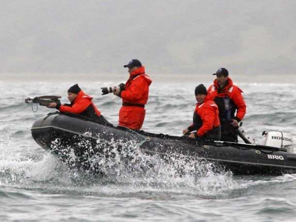 Putin with a crossbow with darts taking part in whale research study with members of the Kronotsky Biosphere Reserve.