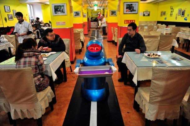 Image: Robot that specialises in delivering food holds an empty plate after serving meals to customers at a Robot Restaurant in Harbin