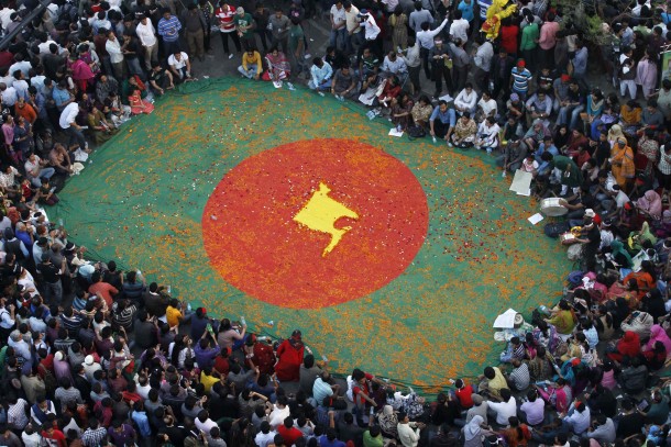 People observe a sit-in protest around a national flag of Bangladesh with a map of the country on it, made by flowers, as they attend a mass demonstration at Shahbagh intersection, demanding capital punishment for Bangladesh's Jamaat-e-Islami senior leader Abdul Quader Mollah, after a war crimes tribunal sentenced him to life imprisonment, in Dhaka February 9, 2013. Thousands of protesters rallied in cities across Bangladesh to demand the execution of an Islamist leader sentenced to life in prison for war crimes committed during the 1971 independence conflict. Picture taken February 9, 2013.  REUTERS/Andrew Biraj (BANGLADESH - Tags: TPX IMAGES OF THE DAY POLITICS CIVIL UNREST)