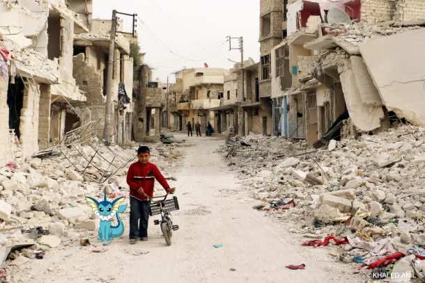 A Syrian boy walks with his bicycle in the devastated Sukari district in the northern city of Aleppo. Credits: Khaled Akil