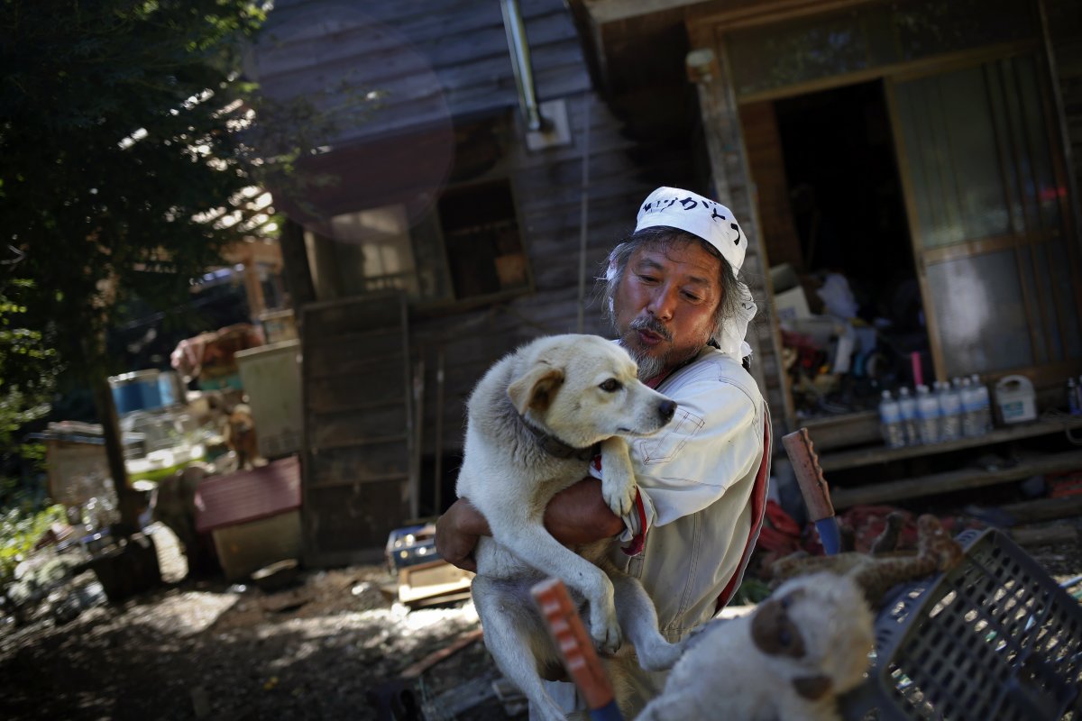 Keigo Sakamoto, 58, holds Atom, one of his 21 dogs and over 500 animals he keeps at his home in the exclusion zone. Sakamoto, a former caregiver and farmer, takes care of the animals with donations and support from outside Fukushima. 