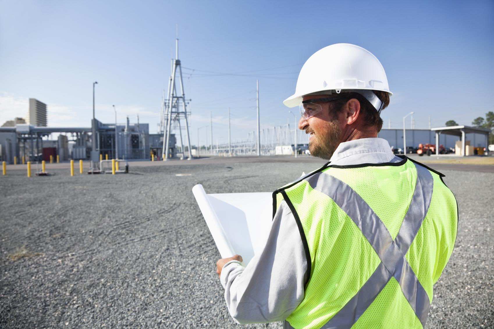 Engineer holding plans surveying power station